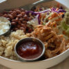 Mexican shredded chicken in a burrito bowl with rice, beans, salsa, and coleslaw